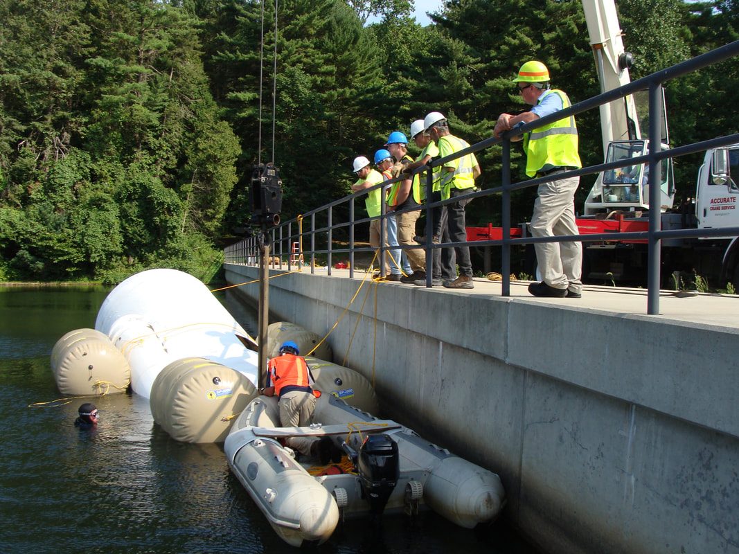 Crew on the Lake Watrous dam walkway as divers in an inflatable boat deploy the aerator floats