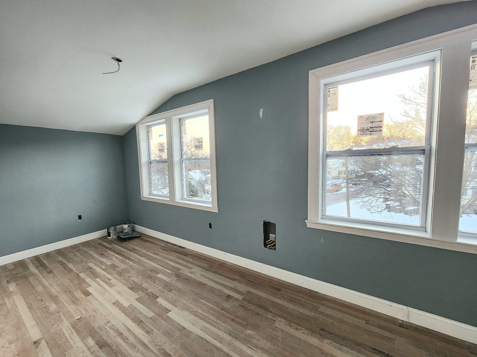 Upstairs bedroom in the addition near completion, with new double-hung windows, painted walls, trim and hardwood floor
